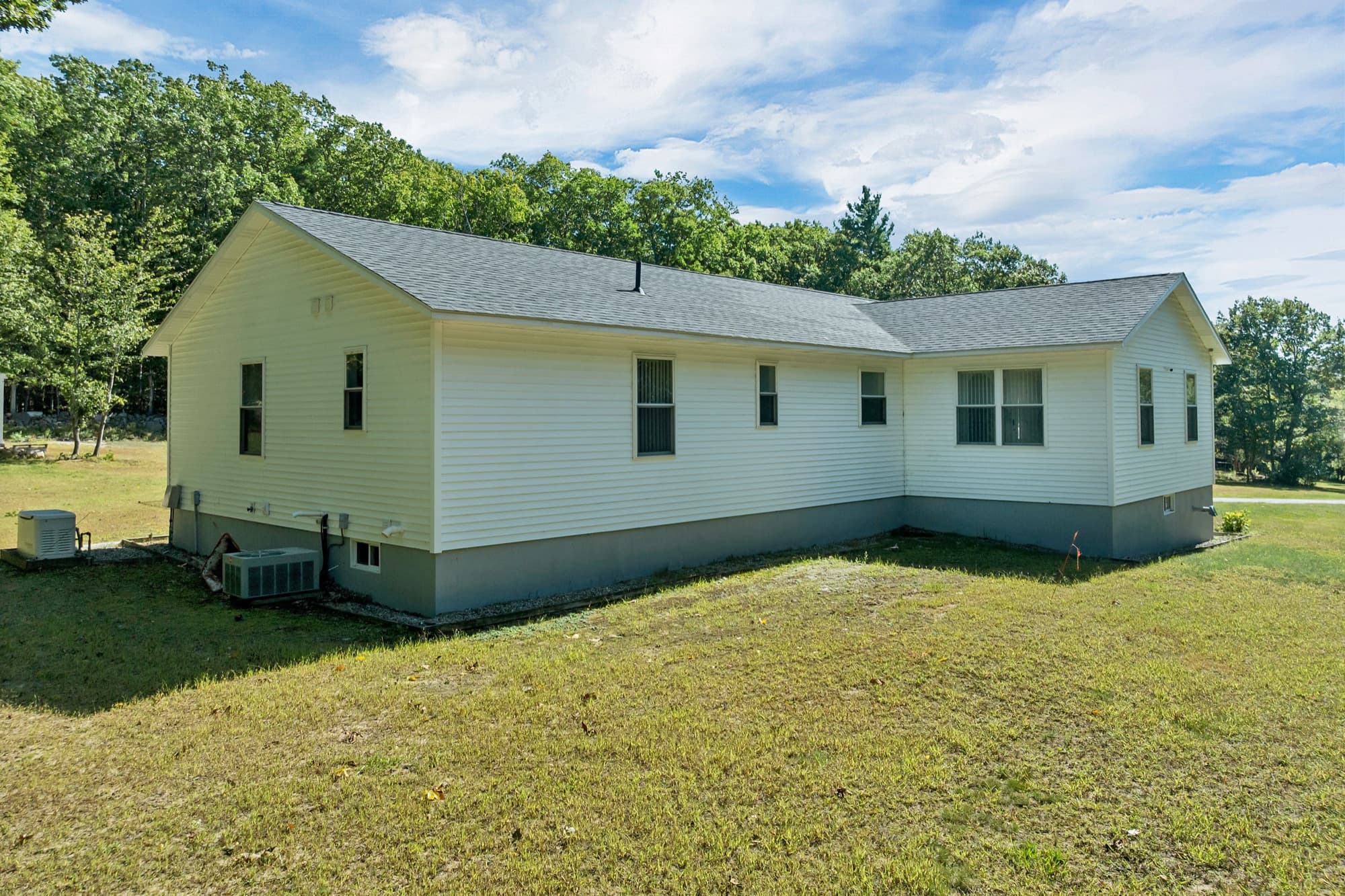 The long back side of the house with the fenced yard and the central air unit
