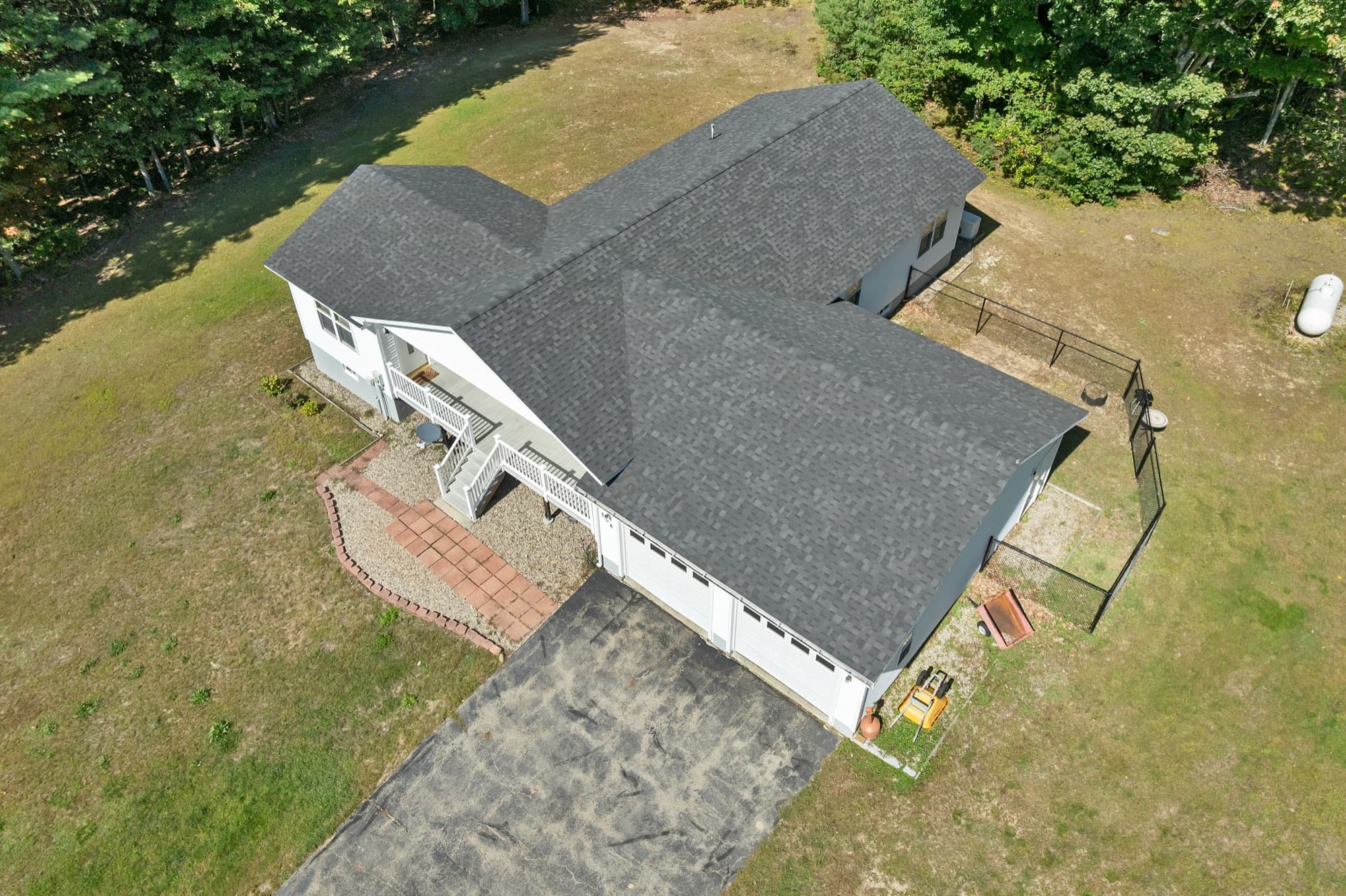 The house and the paved driveway from the air, with the porch and the fenced yard