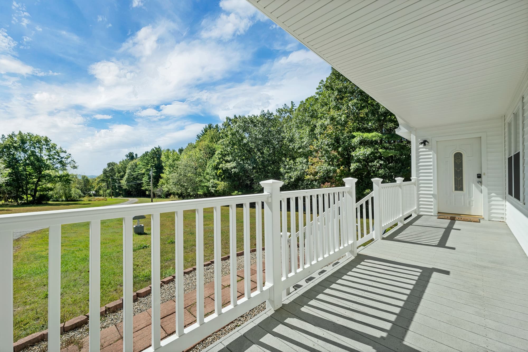 The covered front porch with white railings and the front door