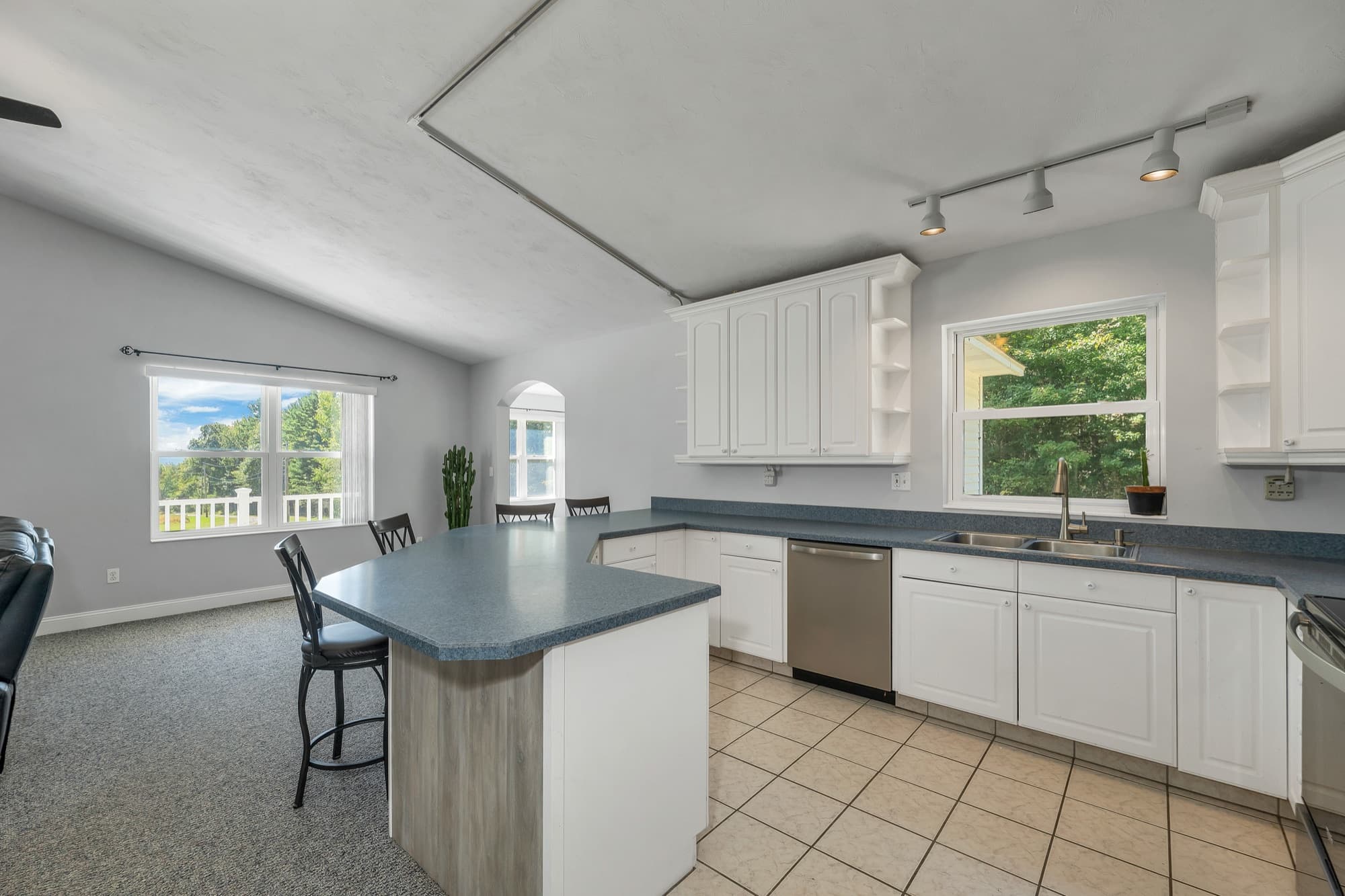 The kitchen with white cabinets, a window over the sink, and the dishwasher, looking toward the dining area