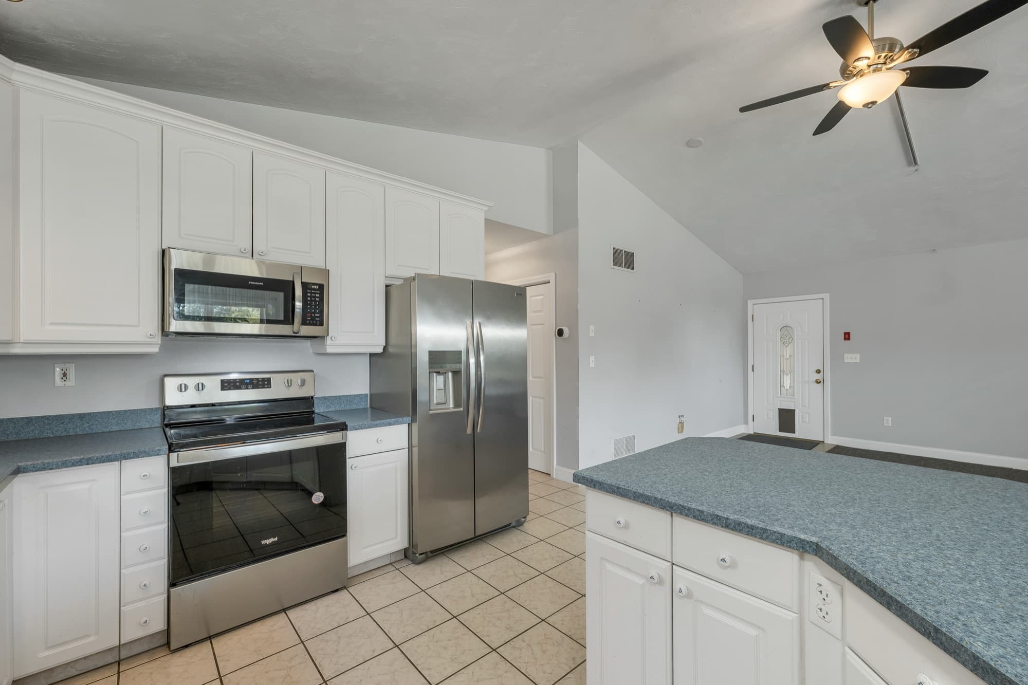 The stainless range, microwave, and refrigerator, with the door to the garage beyond
