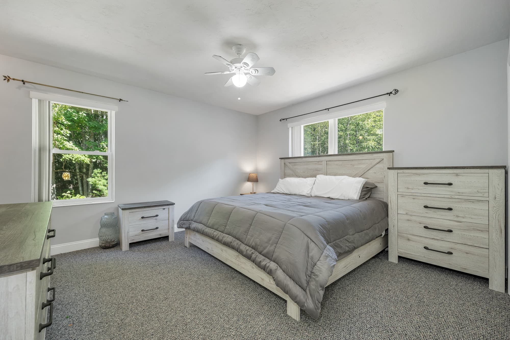 The primary bedroom with 2 windows, carpet, and a ceiling fan